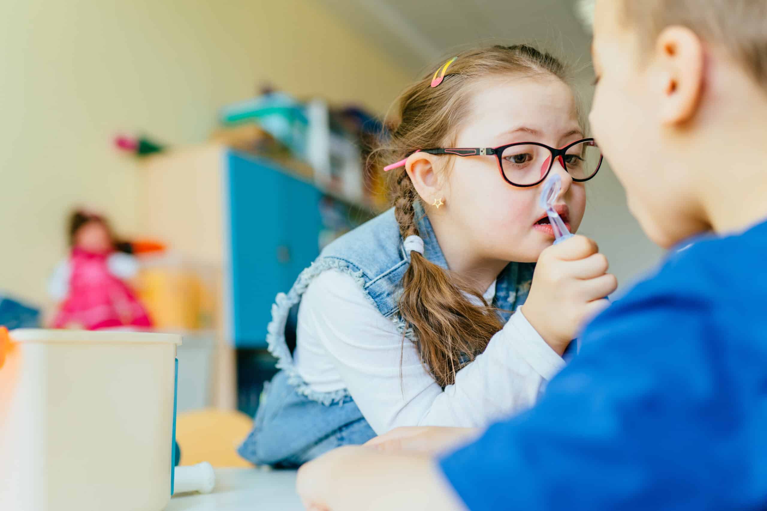 Children with special needs playing dentist with a little girl with Down syndrome using a dental tool on a boy in a school setting