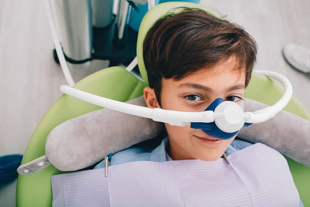 Little boy receiving inhalation sedation during teeth treatment at a dental clinic